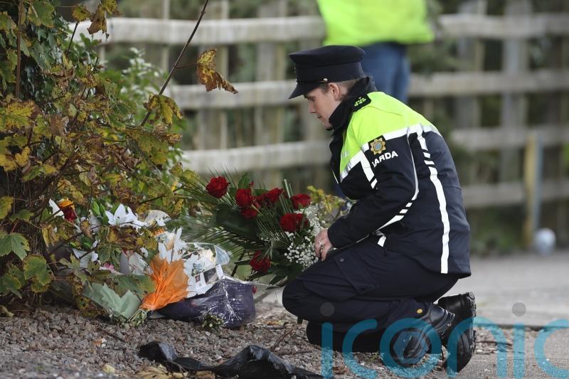 Groups huddle together as family and friends lay floral tributes in Creeslough